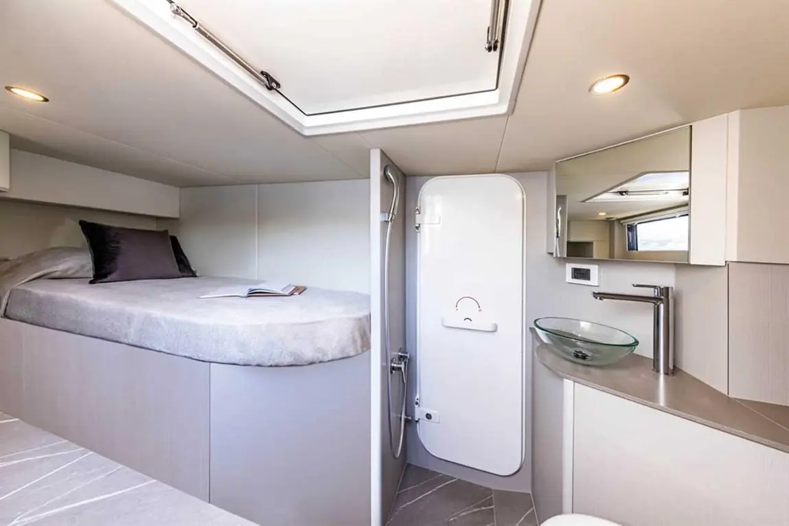 Modern yacht interior featuring a bed, shower, sink, and storage with a neutral palette and stylish design elements.